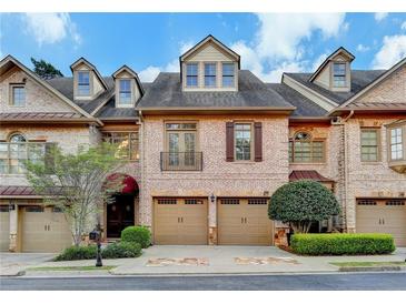 Beautiful brick townhome featuring an attached two-car garage and manicured landscaping for curb appeal at 6273 Clapham Ln, Johns Creek, GA 30097