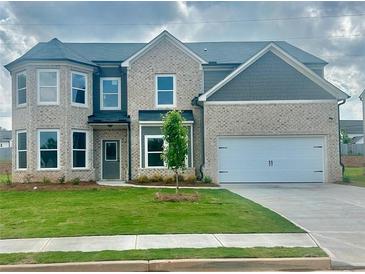 Charming two-story home featuring a brick facade, well-manicured lawn, and a two-car garage at 586 Rodeo Dr, Auburn, GA 30102