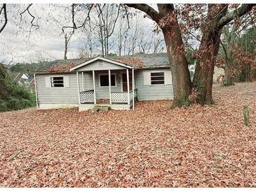 Charming bungalow-style home with a covered front porch surrounded by colorful autumn foliage at 1099 Warren Dr, Riverdale, GA 30296