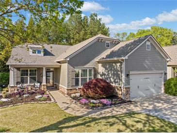 Charming home with a well-manicured lawn, blooming flowerbeds, and a cozy front porch sitting area at 201 Aster Ct, Canton, GA 30114