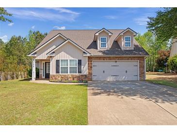 Charming home featuring a two-car garage, stone accents, dormer windows, and a well-manicured lawn at 704 Williamsburg Ct, Villa Rica, GA 30180