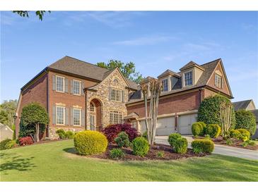 Stately brick and stone home with manicured landscaping on a lush green lawn and three-car garage at 895 Ovalene Sw Ln, Marietta, GA 30064