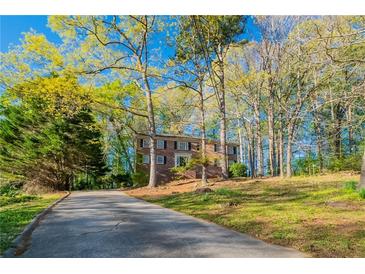 Charming two-story brick home with a long driveway surrounded by lush trees and greenery at 4510 Trumble Ter, Snellville, GA 30039