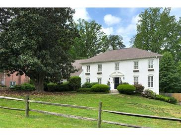 Charming white brick two-story home with well-manicured lawn and mature trees at 7000 Hunters Knl, Atlanta, GA 30328