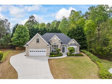 Charming brick home featuring an attached two-car garage, manicured lawn, and lush landscaping at 3601 Cedar Springs Ln, Loganville, GA 30052