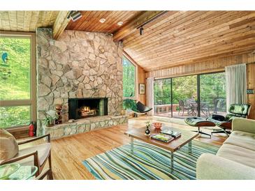Inviting living room with stone fireplace, hardwood floors, and expansive windows overlooking the lush outdoor scenery at 2208 Guinevere Ne Way, Atlanta, GA 30345