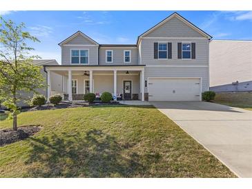 Charming two-story home featuring a welcoming front porch and well-manicured lawn at 81 Creekside Bluff Way, Auburn, GA 30011