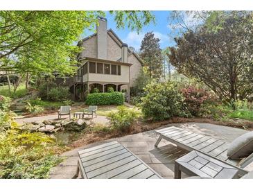 Expansive backyard featuring lush landscaping, stone patio, pond, and cozy lounge chairs for ultimate relaxation at 3749 Watkins Ne Pl, Brookhaven, GA 30319