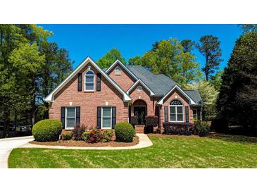 Charming brick home featuring manicured landscaping, black shutters, and an arched entryway, offering great curb appeal at 2319 Lochinver Ln, Conyers, GA 30094