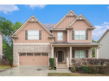 Charming two-story home with brick and siding, attached garage, and a cozy covered front porch at 859 Walking Stick Trl, Auburn, GA 30011