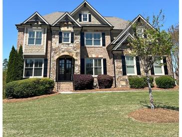 Stunning stone and brick home with manicured lawn, mature landscaping, and charming architectural details at 2671 Moon Chase Ln, Buford, GA 30519