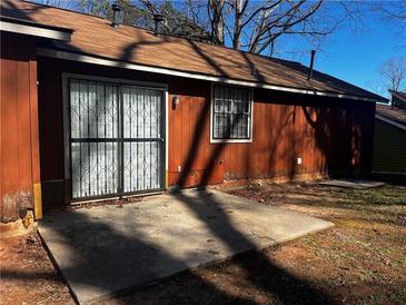 View of the home's exterior highlighting a concrete patio and sliding door to the home at 4071 River Rd, Ellenwood, GA 30294