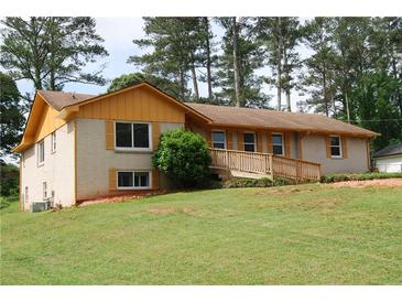 Charming ranch-style house with yellow accents, a brick facade, and a welcoming front yard with mature trees at 1584 Hebron Ln, Riverdale, GA 30296