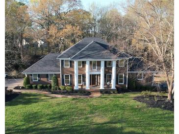 Stately brick home with columned porch and lush landscaping on expansive manicured lawn at 5254 Franklin Goldmine Rd, Cumming, GA 30028