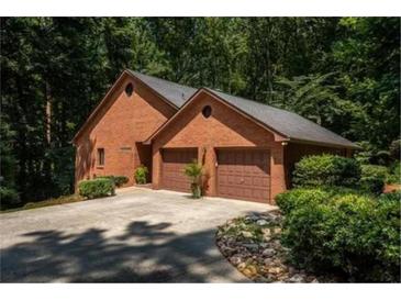 View of the brick home's exterior showcasing a two-car garage and mature landscaping surrounding the property at 5325 Pheasant Run, Stone Mountain, GA 30087