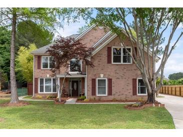 Charming two-story brick home with manicured lawn and inviting front porch with rocking chairs at 5300 Coacoochee Ter, Johns Creek, GA 30022