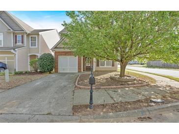Charming two-story home featuring a well-maintained front yard with mature tree, a driveway, and attached garage at 200 Arrowhead Ln, Canton, GA 30114