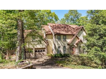 Two-story home featuring an attached two-car garage and landscaped yard with mature trees at 3200 Country Club Nw Ct, Kennesaw, GA 30144