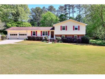 Charming two-story home with a well-manicured lawn, a two-car garage, and mature trees surrounding the property at 4172 Whispering Forest Ct, Lilburn, GA 30047