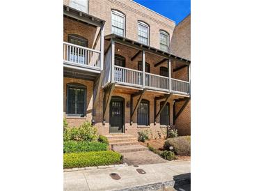 Charming brick townhouse featuring a covered porch and well-maintained landscaping at 9062 Selborne Ln, Palmetto, GA 30268