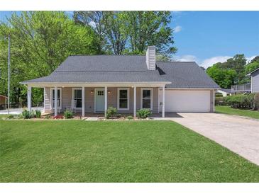 Charming home featuring a covered front porch with rocking chairs and a well-manicured lawn at 115 Braided Blanket Blf, Johns Creek, GA 30022