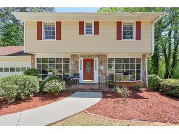 Charming two-story home featuring stone accents, a red front door, well-maintained landscaping, and bright red window shutters at 1423 Fairfield Sw Dr, Lilburn, GA 30047