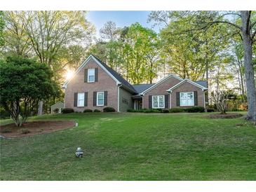Charming brick home with a well-manicured lawn and mature trees offers inviting curb appeal at 2380 Emerald Dr, Loganville, GA 30052