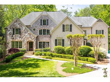 Inviting traditional home featuring a stone facade, manicured lawn, and lush landscaping at 5178 S Trimble Rd, Atlanta, GA 30342