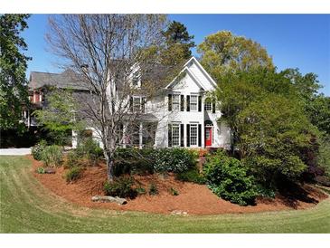 Charming two-story home with a manicured lawn, lush landscaping, and a welcoming red front door at 1485 Mill Place Dr, Dacula, GA 30019