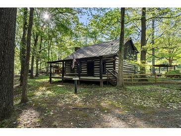 Charming log cabin with a covered front porch nestled among mature trees at 3401 Clay Rd, Austell, GA 30106