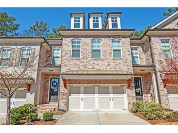 Charming brick townhome with a two-car garage and a well-maintained front yard at 5022 Towneship Creek Rd, Roswell, GA 30075