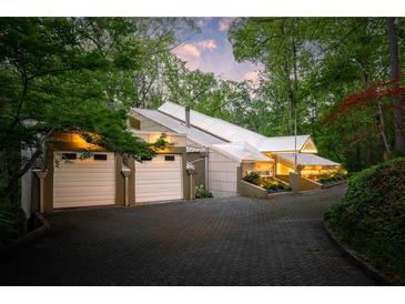 Unique modern home exterior with a striking white roof, two-car garage, and lush landscaping at 1121 Dawn View Nw Ln, Atlanta, GA 30327