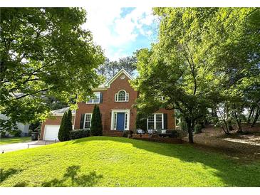 Charming two-story brick home with a well-manicured lawn, mature trees, and a welcoming blue front door at 4213 Schooner Ne Ct, Roswell, GA 30075