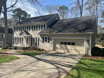 Traditional two-story home featuring a welcoming porch, attached two car garage, and well-maintained lawn at 7260 Dunhill Ter, Atlanta, GA 30328
