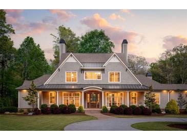 Charming home with a manicured front lawn, mature landscaping, and a welcoming facade with a covered entry at 7305 Breeze Bay Rd, Cumming, GA 30041