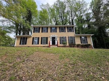 Traditional two-story home with tan siding, black shutters, and mature trees in a large front yard at 5183 Mccarter Ct, Stone Mountain, GA 30088