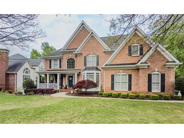 Elegant brick home showcasing a manicured lawn, covered porch, and classic architectural details at 710 Bentgrass Ct, Dacula, GA 30019