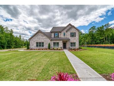 Beautiful, two-story home featuring a brick facade, manicured lawn, and inviting walkway at 700 Relic Rdg, Hampton, GA 30228