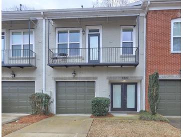 Charming townhouse featuring light gray brick, a balcony, and a single-car garage at 5883 Brookside Oak Cir, Norcross, GA 30093