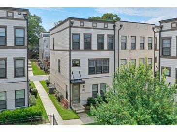 A modern two-story townhome featuring neutral siding, a brick accent wall, and manicured landscaping at 2032 Holtz Ln, Atlanta, GA 30318