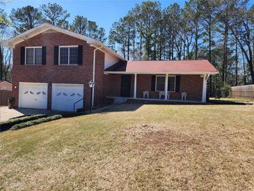 Charming brick home with a two-car garage and a cozy front porch nestled among mature trees in the yard at 2117 Chestnut Hill Cir, Decatur, GA 30032