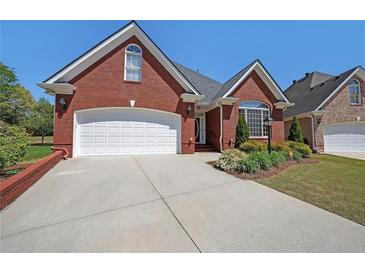 Charming brick home with a two-car garage, manicured landscaping, and a well-maintained lawn at 1610 Glenhurst Dr, Snellville, GA 30078