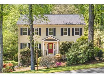Charming two-story home with a red door and black shutters, surrounded by mature trees and lush landscaping at 2441 Mitchell Ne Rd, Marietta, GA 30062