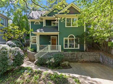 Inviting green home with well-maintained landscaping and a charming front porch entry at 446 Harold Ne Ave, Atlanta, GA 30307