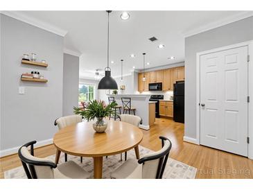 Bright dining area with modern lighting fixtures, light wood flooring, and views to the kitchen at 4201 Stratford Commons, Decatur, GA 30033