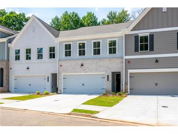 Charming townhouse with brick accents, a two-car garage, and well-maintained landscaping at 166 Bluffington Way, Marietta, GA 30066