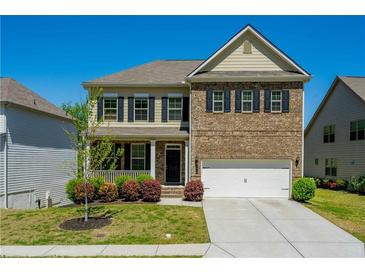 Charming two-story home featuring a brick facade, well-manicured lawn, and a covered front porch at 2649 Ogden Trl, Buford, GA 30519