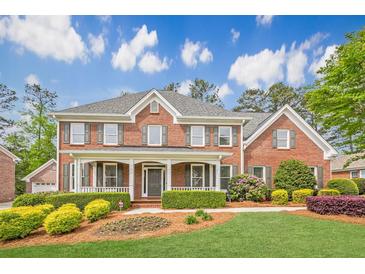 Charming two-story brick home featuring a welcoming front porch and beautifully landscaped front yard at 1611 Threepine Pl, Lilburn, GA 30047