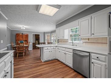 Traditional kitchen features white cabinetry, stainless appliances, and hardwood flooring at 4128 Mayflower Sw Ct, Lilburn, GA 30047