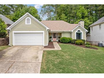 Charming home featuring a well-manicured lawn, complemented by a 2-car garage and a delightful pink front door at 1970 Glen Eves Dr, Roswell, GA 30076